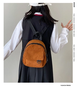 Detail view of the brown corduroy mini backpack with black straps and zip closure
