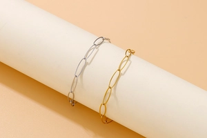 Detailed view of gold and silver stainless steel oval link bracelets on a display stand