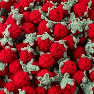Macro shot showing detailed texture of handmade red crochet strawberry accessories