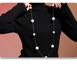 Long collier en acier inoxydable argenté avec perles blanches sur pull noir