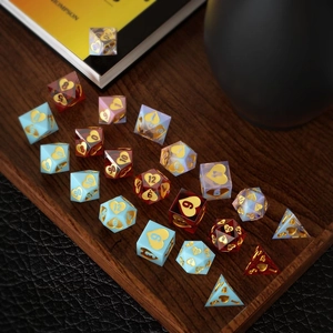 Coffret de dés polyédriques JdR avec motifs de cœurs dorés disposés sur plateau en bois