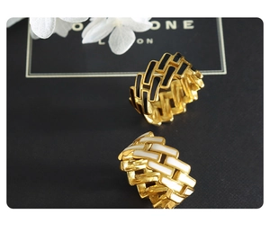 Close-up of gold titanium steel rings with black and white enamel cross pattern