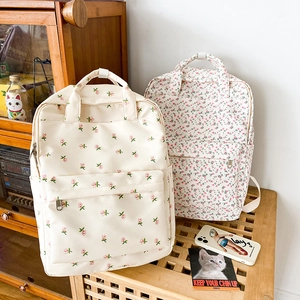 Detail of floral school backpacks in beige and pink with front zipper pockets