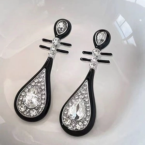 Close-up of elegant black enamel drop earrings with sparkling rhinestones and metal finish