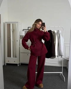 Detail of burgundy two-piece tracksuit with zip-up high neck top and wide-leg joggers