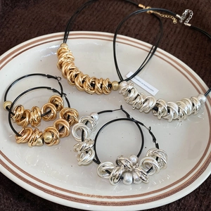 Detail of twisted round metal pendants on black leather cords in a vintage jewelry set