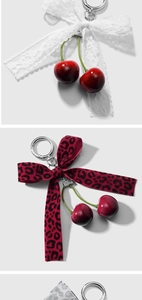 Detailed view of cherry keychains with lace and leopard print bows on clean background