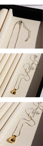 Macro detail of golden teardrop pendant on silver snake chain with lobster clasp
