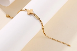 Detail of golden stainless steel paperclip chain bracelet with a cross pendant