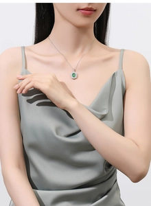 Close-up of elegant S925 silver necklace with green emerald pendant and halo diamonds