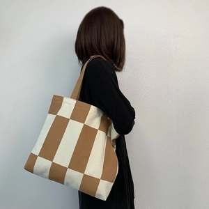Detail of checkered canvas tote bag with brown straps for casual daily outfit
