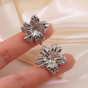 Vue macro de boucles d'oreilles fleurs argentées sur fond de satin élégant en main