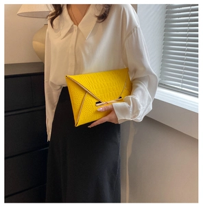Gros plan d'une pochette jaune motif crocodile avec des détails de bordure en métal doré
