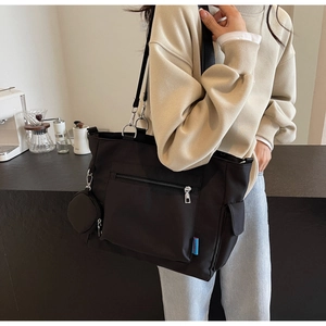 Close-up of black Oxford cloth tote bag with front zipper pocket and round coin purse charm