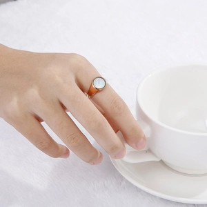 Rose gold stainless steel ring with white shell inlay shown on a model's hand