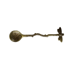 Retro brass spoon with dragonfly detail and artistic branch handle on white background
