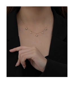 Close-up of gold 925 silver necklace with sparkling star and moon charms on model