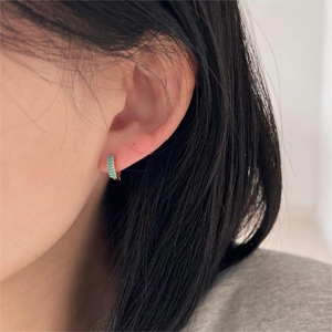 Close-up of gold hoop earring with turquoise rectangular stone worn by a model