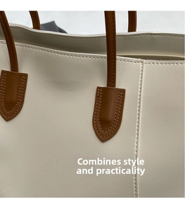 Close-up of reinforced U-shaped stitching on beige tote bag with brown leather strap