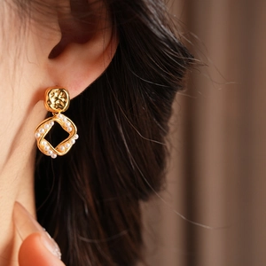 Close-up of gold plated square knot pearl earrings worn by a model in French vintage style