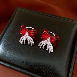 Close-up of red ribbon bow clip earrings with dangling white zircon tassels and silver metal
