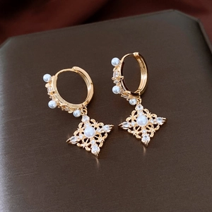 Détail macro de boucles d'oreilles losanges plaquées or 18K avec perles et strass