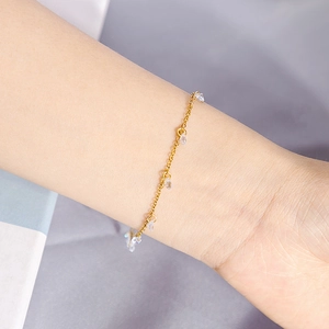 Close-up of a delicate gold chain bracelet with clear crystal charms on a woman's wrist