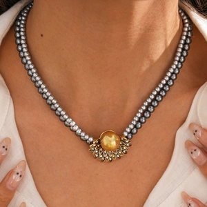 Primo piano di una collana di perle grigie a doppio strato con pendente dorato e strass
