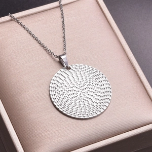 Detailed view of silver textured round pendant necklace with spiral engraved pattern