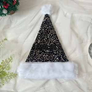 Detail of black Christmas hat with golden sequins and white plush trim on fabric background