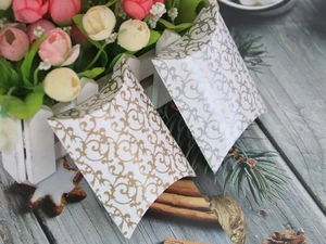 Detail of silver and gold pillow gift boxes with European floral patterns on wood
