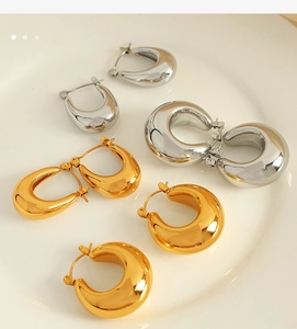 Detailed display of chunky gold and silver hollow hoop earrings on a ceramic tray