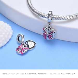 Macro shot of heart-shaped silver charm with pink bow enamel and Happy holidays engraving