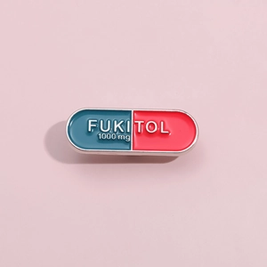 Close-up of blue and red enamel capsule pin with white Fukitol 1000mg text on pink background