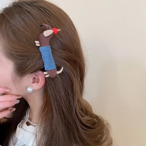 Detail of the cute brown fabric dachshund hair clip on a model's wavy hair