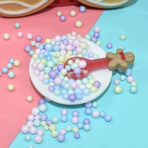 Miniature gingerbread man spoon in a bowl of colorful foam beads for DIY crafts