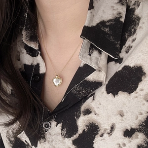 Elegant 925 sterling silver heart shell pendant necklace worn on a gold chain