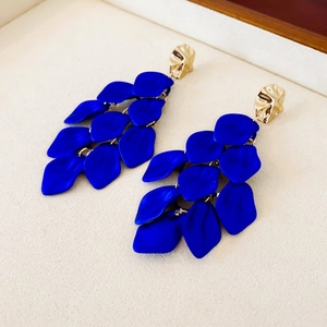 Detail of dark blue petal tassel earrings with textured gold top on beige velvet