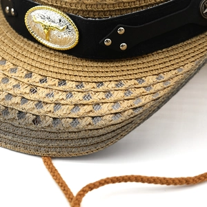 Close-up of woven straw cowboy hat featuring metallic bull head buckle and studded leather band