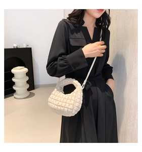 Detailed shot of cream quilted crossbody bag featuring cloud pleats and lattice texture