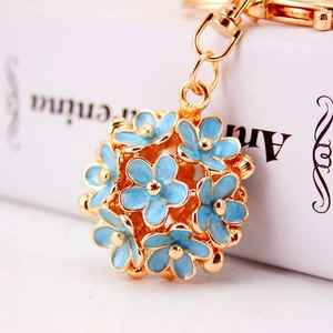 Macro shot of gold metal ball pendant with blue enamel flowers and golden bead centers