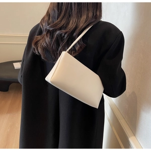 Minimalist white leather underarm bag shown on a model with a black coat for contrast