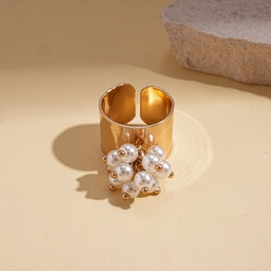 Close-up of golden wide open ring featuring clustered white pearls and beads