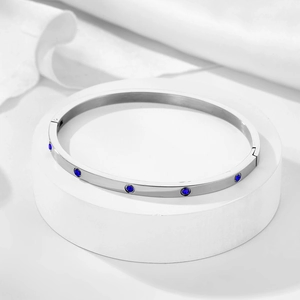 Close-up of silver steel bangle with blue round zircon stones and a hinged clasp