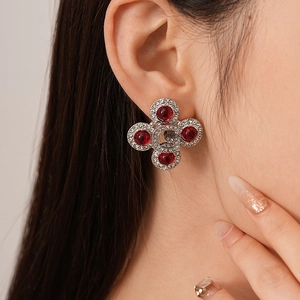 Close-up of vintage resin rhinestone cross earrings with G letter on model's ear