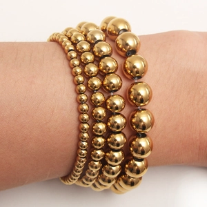 Minimalist 4-piece set of gold-plated stainless steel beaded bracelets on a female wrist