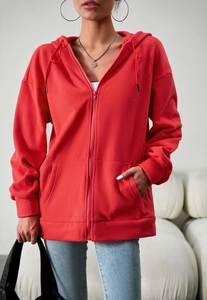 Detail of red fleece zip-up hoodie featuring a drawstring hood and kangaroo pockets