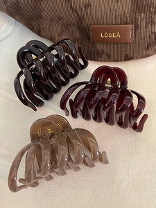 Close-up of three acrylic striped shark hair claws in autumn coffee and burgundy tones
