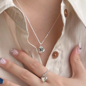 Silver teardrop pendant necklace and heart ring worn with elegant cream silk blouse