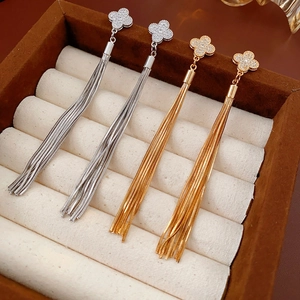 Detailed view of gold and silver tassel earrings with zircons in a jewelry box